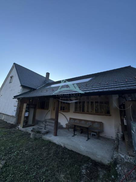 A family house in Demandice with a seating area in the yard and a gentle slope.