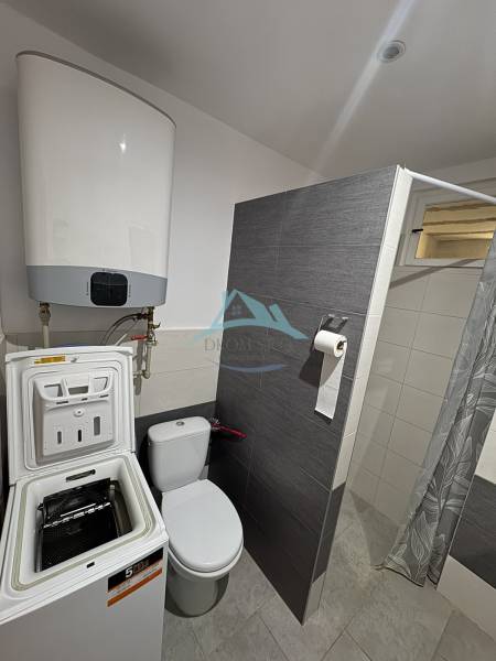 A bathroom in a family house with a washing machine, toilet, and shower.