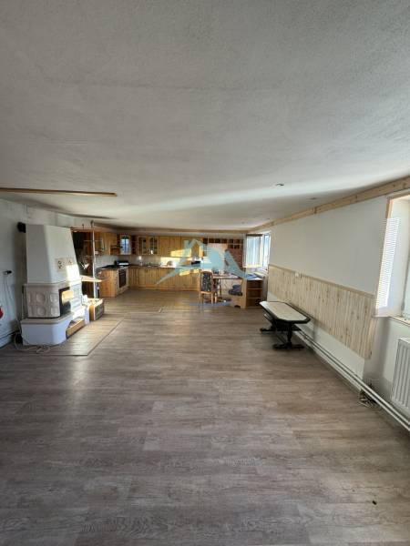 Interior of a family house with a kitchenette, a masonry stove, and a wooden-patterned floor.