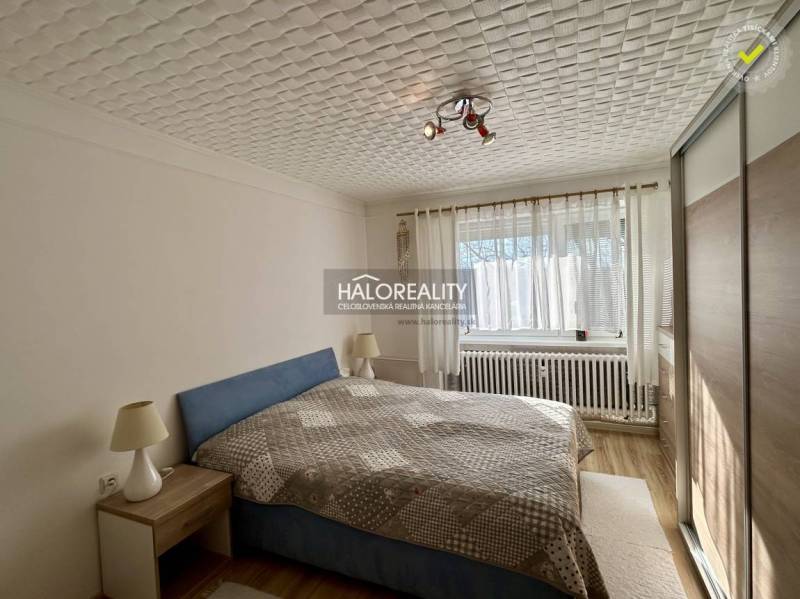 A bright bedroom with a ceiling light and wood-patterned flooring in a two-room apartment.