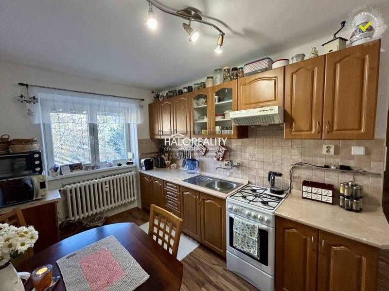 A kitchen in a 2-room apartment with a wooden floor decor and classic cabinets.