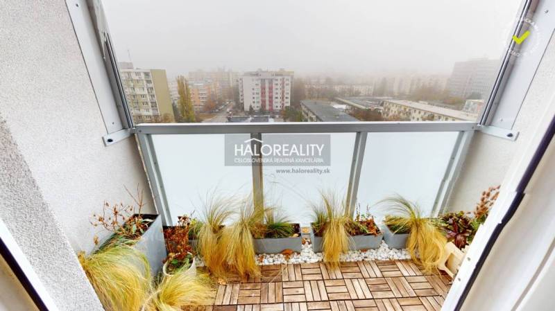 Balcony of a 3-room apartment in Bratislava - Ružinov with a view of the misty city, wooden floor decor.