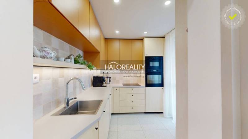 A kitchen in a 3-room apartment with a white kitchen unit, a stainless steel sink, and built-in appliances.
