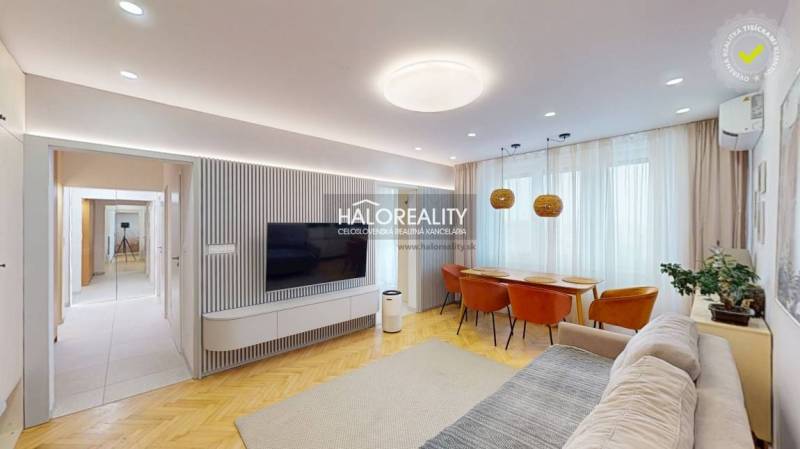 Living room in a 3-room apartment with a TV on the wall, a sofa, and a dining table.