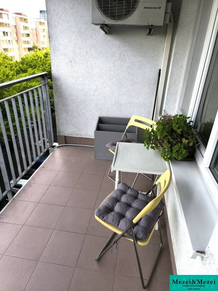 A balcony of a 2-room apartment in Bratislava with chairs and greenery, suitable for relaxation.