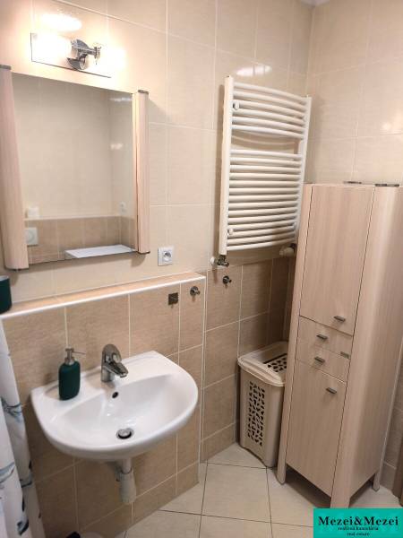 Bathroom in a 2-room apartment with a sink, cabinet, and towel-drying radiator.