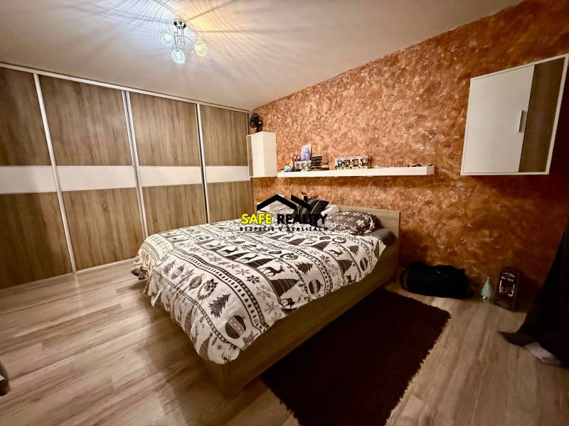 Bedroom in a two-room apartment with a bed, storage space, and a wooden decor floor.