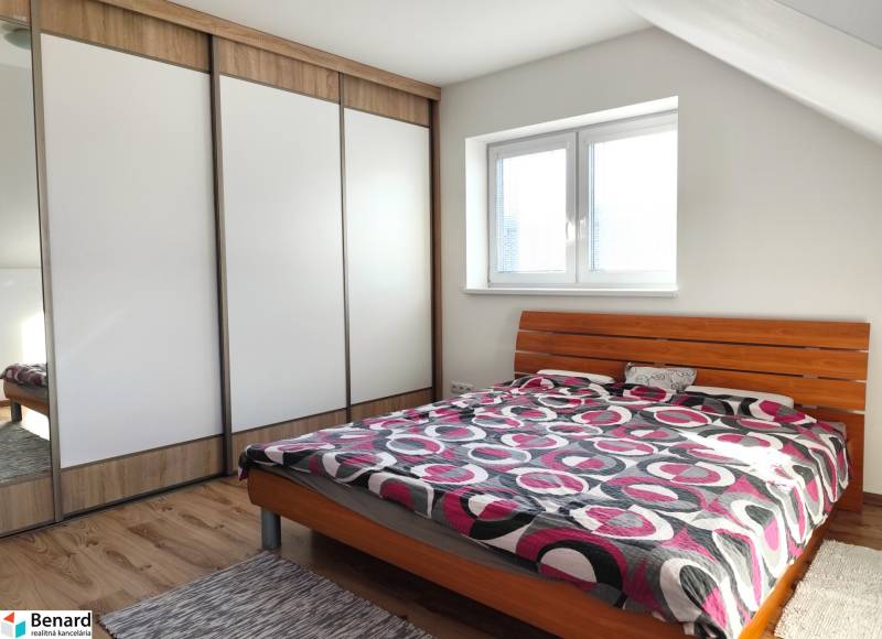 The bedroom in the family house contains a bed, a wardrobe, and a floor with a wooden decor.