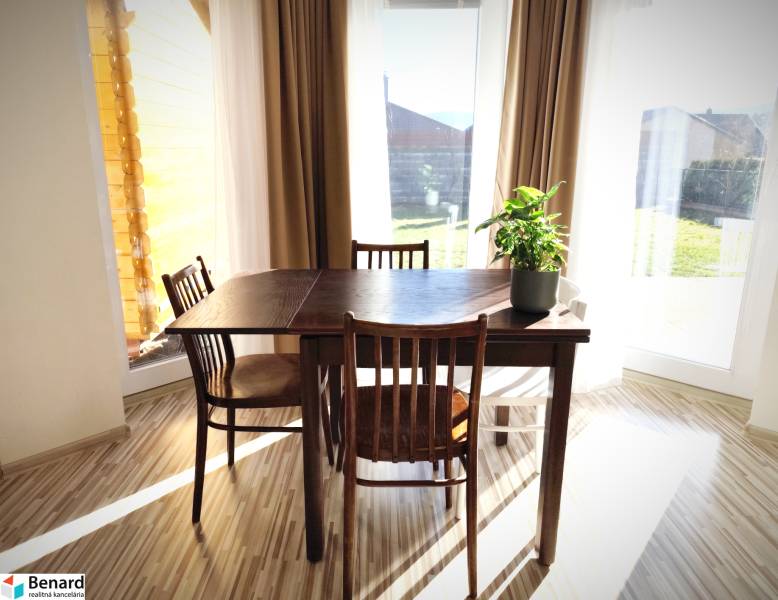 Dining table with a plant and chairs on a wooden-decor floor in a family house.