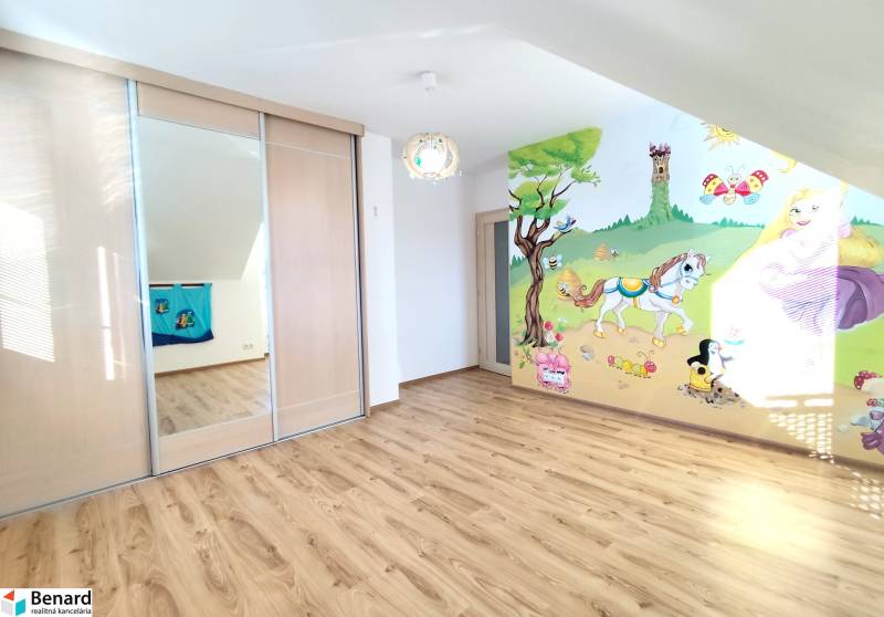 Children's room with wood-patterned flooring, sliding wardrobe, painted wall with a nature motif.