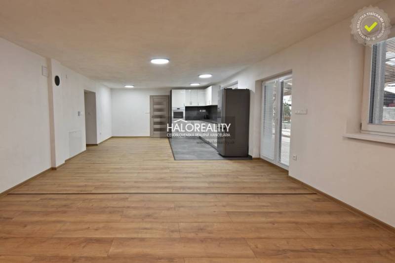 Living room in a family house with a kitchen, wooden decor flooring, white walls.