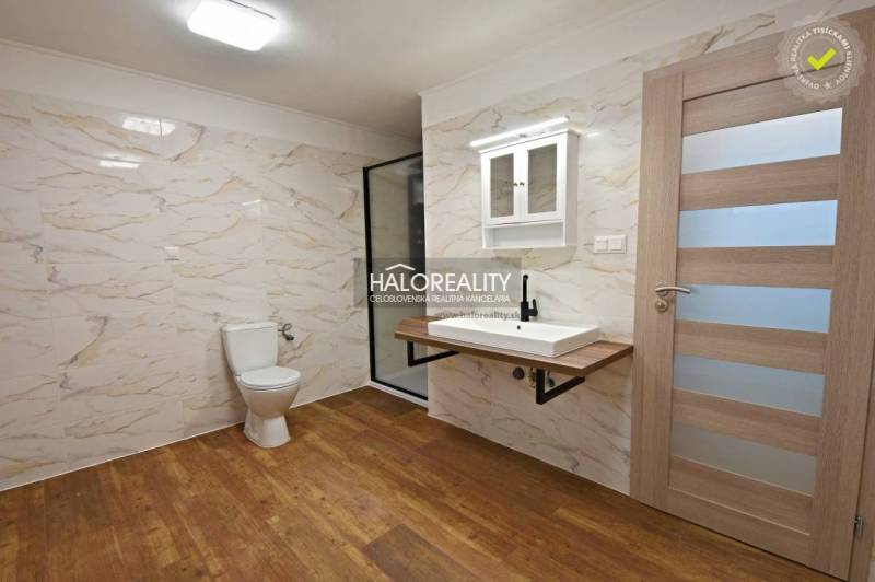 A bathroom in a family house with a wooden decor floor, a sink, and a shower enclosure.
