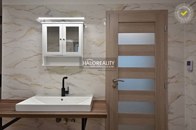 A bathroom with a sink, a black faucet, and a cabinet in a family house.