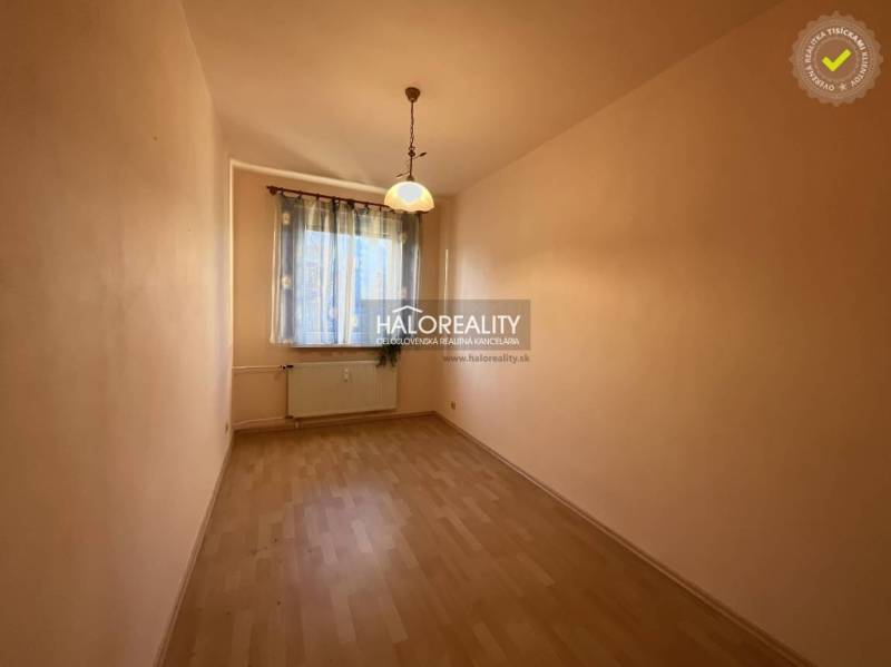 A narrow bright space with a window, curtains, and a wooden decor floor in a 3-room apartment.