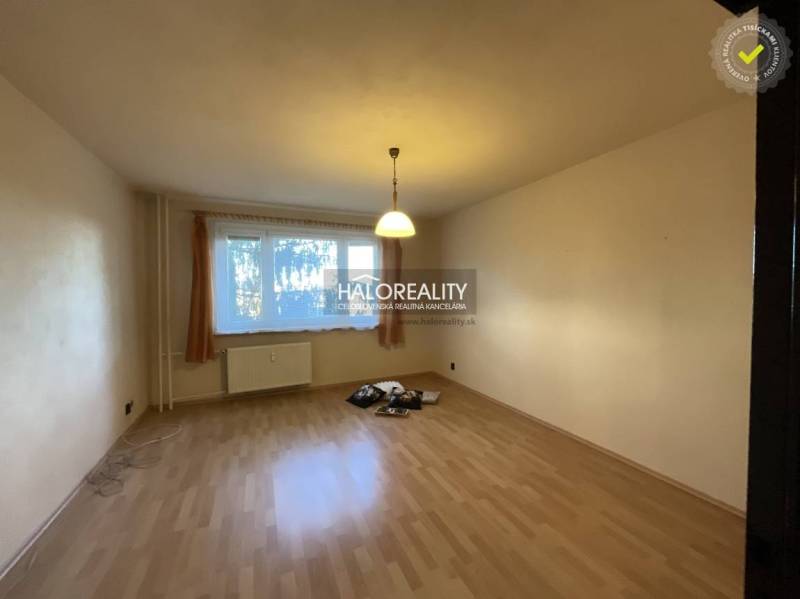Living room in a three-room apartment with a wood-patterned floor and a large window.
