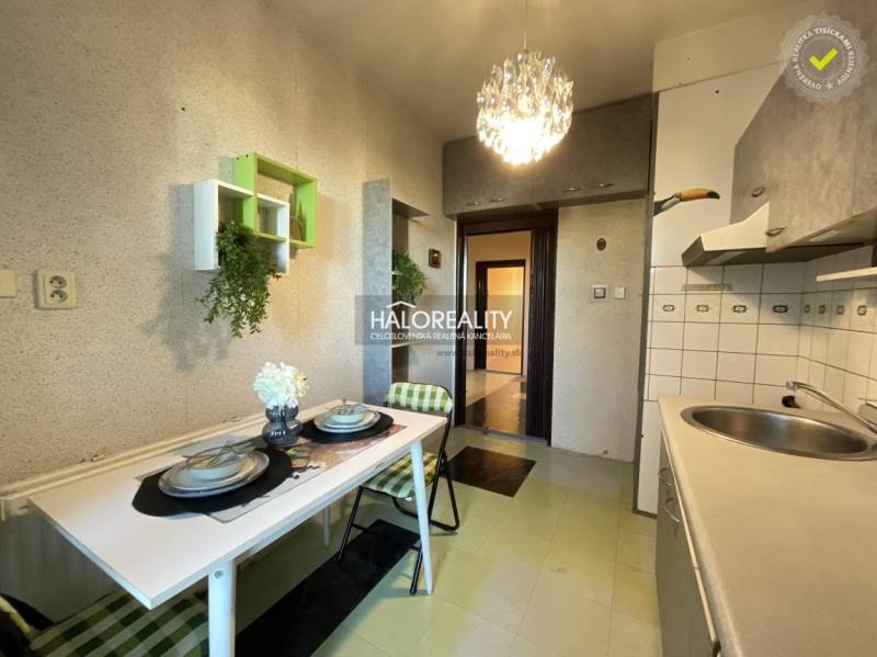 A kitchen in a 3-room apartment with a table, chairs, and decorations, ideal for dining.