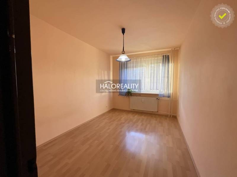 Empty room with a window, curtain, wood-patterned floor, light, and radiator.