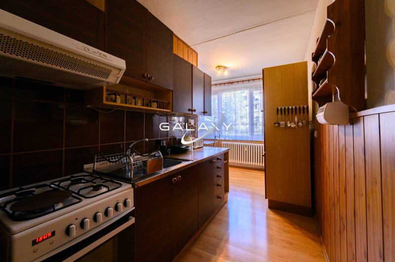 A kitchen in a 2-room apartment with a countertop and floor with a wood decor.
