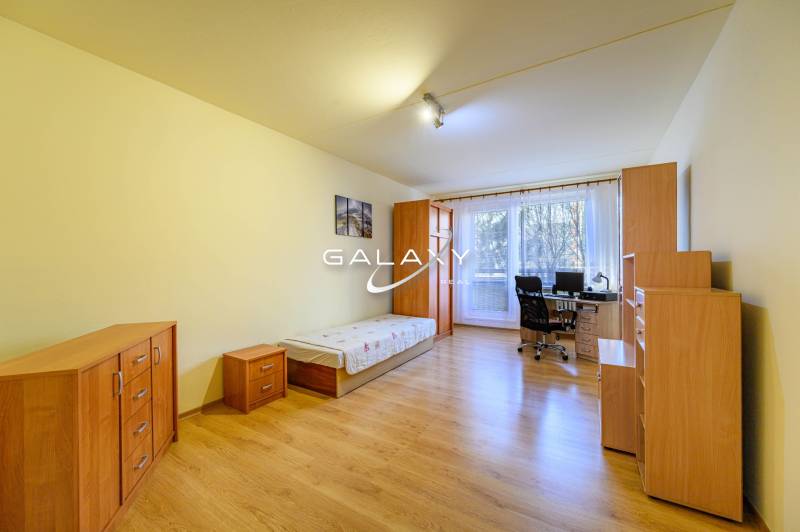 Room in a 2-room apartment; bed, desk, wardrobes, floor with wood decor.