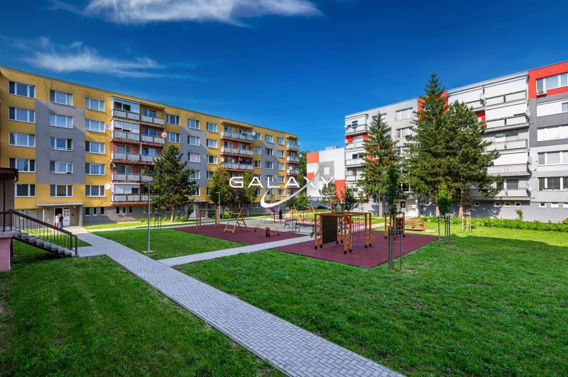 Playground between apartment buildings on Sládkovičova Street in Fiľakovo, surrounded by greenery.