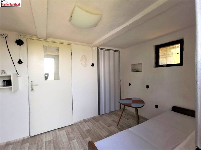 Simple interior, white cottage, small table, light floor, door with window, recreational area.