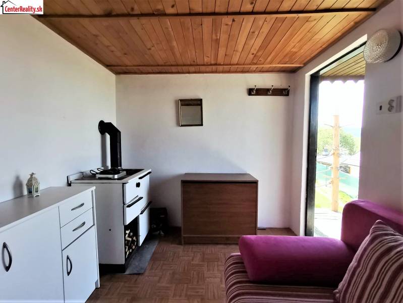 In the chat kitchen, there is a stove, a cabinet, a pink sofa, and a view of the garden.