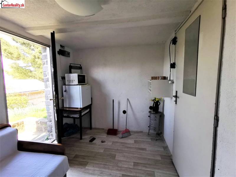 Interior of a cabin with appliances, a sofa, and a view of the outdoor nature.