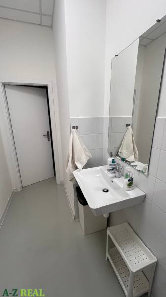 Bathroom in offices with a sink, towels, and cleaning supplies.
