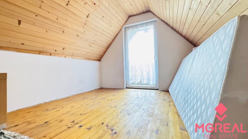Attic room in a cottage with a wooden decor floor and a skylight.
