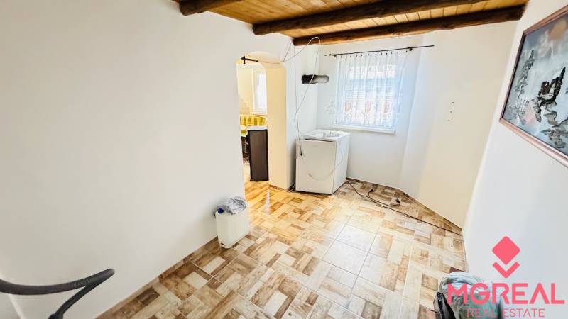 Interior of a cabin with wood-patterned flooring, washing machine, arched entrance to the kitchen.