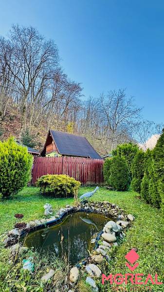 A cottage in Partizánske, surrounded by a garden with an artificial pond and sculptures.