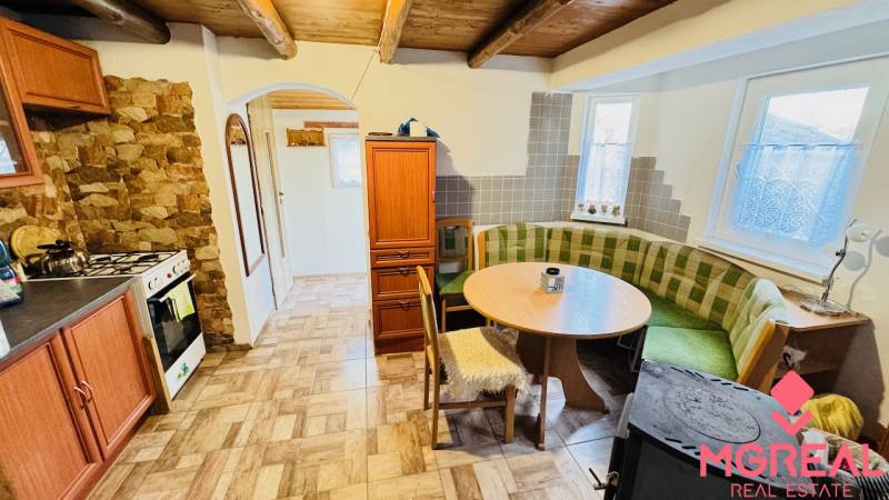 A rustic kitchen in a cottage with a gas stove and a corner sofa.