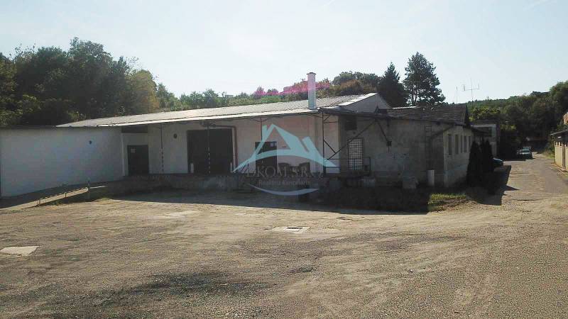 Warehouses and halls on Železničná Street in Veľký Krtíš surrounded by trees.