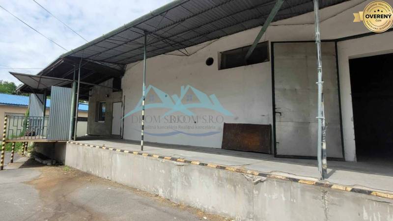 Covered loading ramp on Železničná Street near warehouses and halls with steel structures.