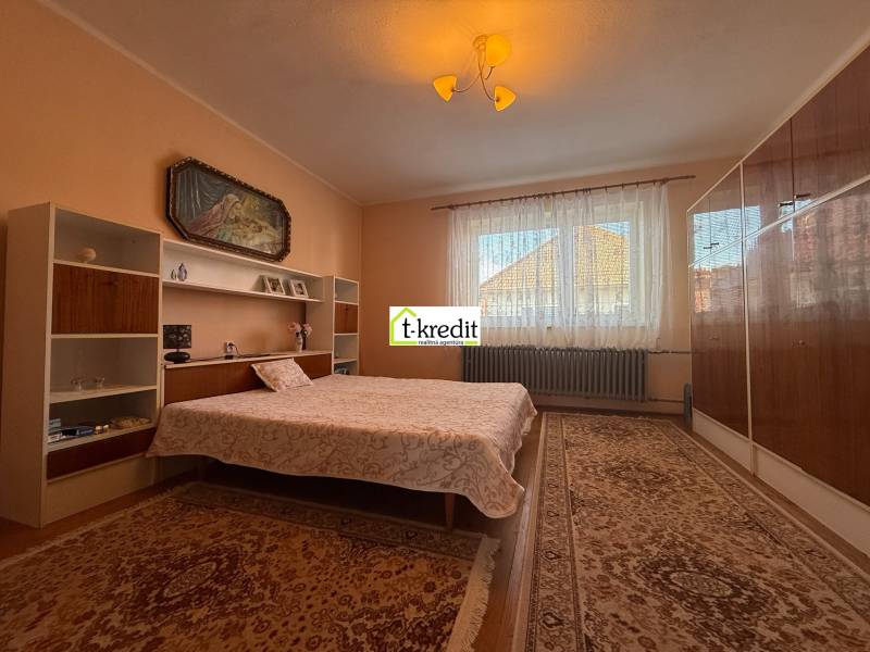 Bedroom with carpets, bed, shelves, and a painting in a family house.