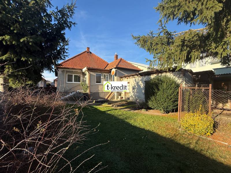 A family house in Machulince with a red tiled roof, a garden, and mature trees.