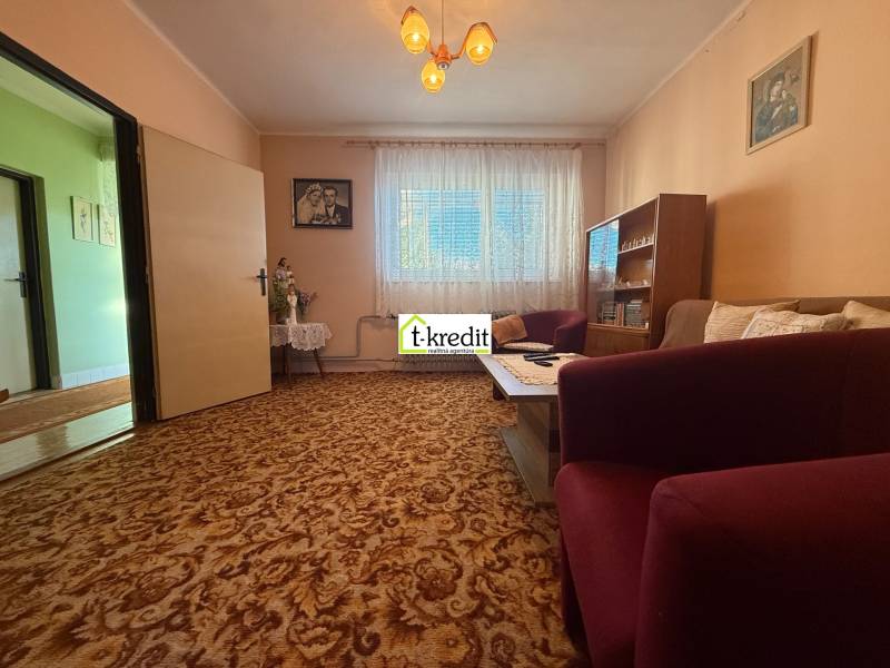 Living room in a family house with carpeted floor, furniture, and curtains.