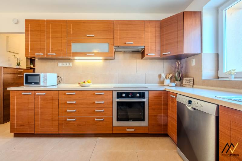 A kitchen with wooden decor, built-in appliances, and a microwave in a 2-room apartment.