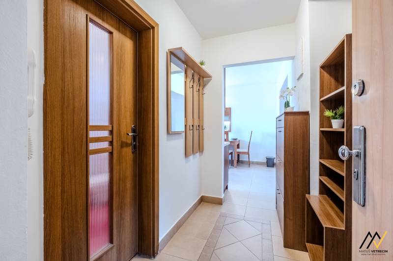 Entrance hallway in a 2-room apartment with wooden decor, featuring a coat rack and a mirror.