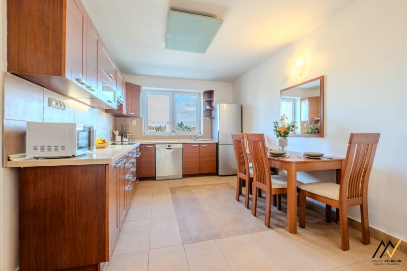 A kitchen in a 2-room apartment with a wooden decor and a dining table.