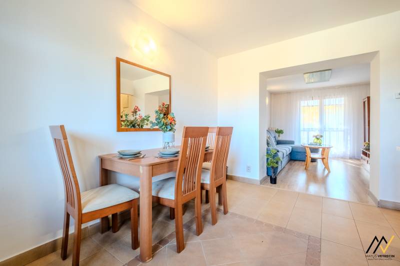 Bright dining room with a wooden table in a 2-room apartment, floor with wooden decor.