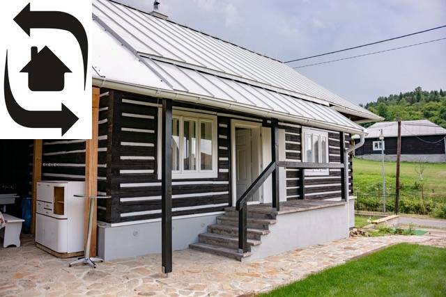 A cottage in Legnava with a wooden facade and a paved terrace, surrounded by greenery and nature.