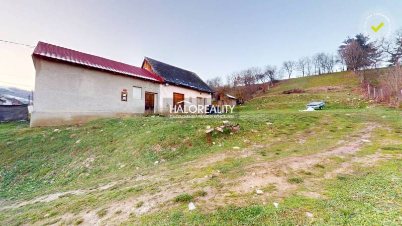 A family house in Klenovec on a slope, with a nearby bench and green surroundings.