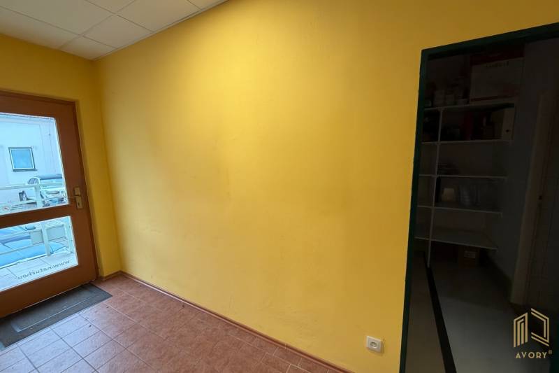 Yellow wall and glass doors in commercial space with brown flooring.