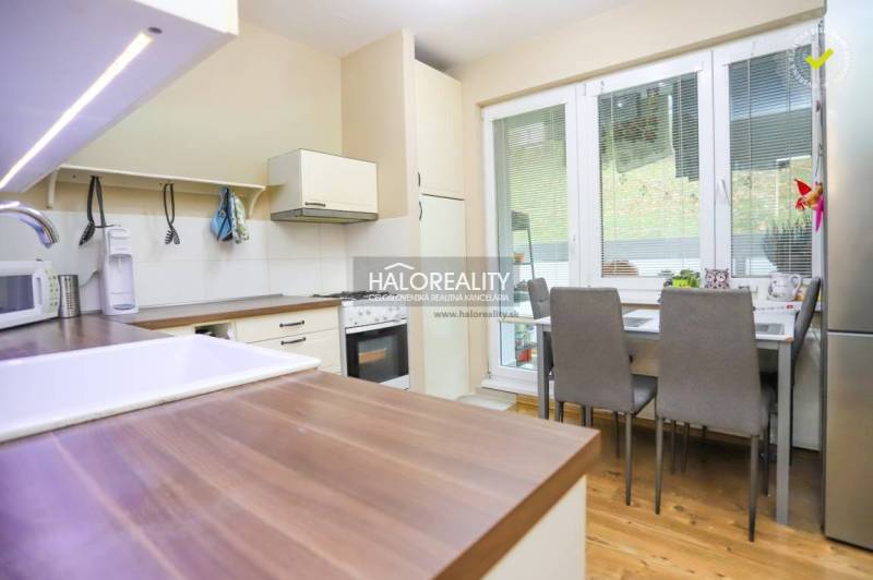 A kitchen in a 2-room apartment with a wood-patterned floor, a dining table, and appliances.
