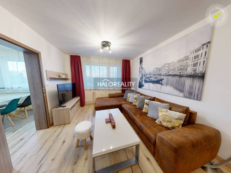 Living room in a two-room apartment with a brown sofa and a wooden decor floor.