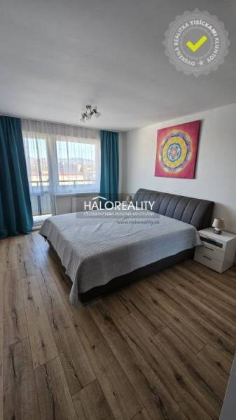 Bedroom in a 2-room apartment with a wooden decor floor and art on the wall.