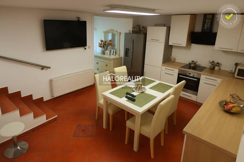 A kitchen in a family house with a tiled floor, a dining table, and a kitchen unit.