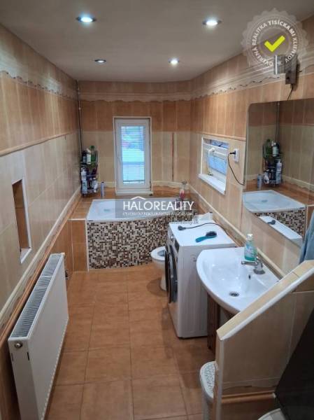 Bathroom with a bathtub, sink, and washing machine in a family house. Soft tones and ceramic tiles.