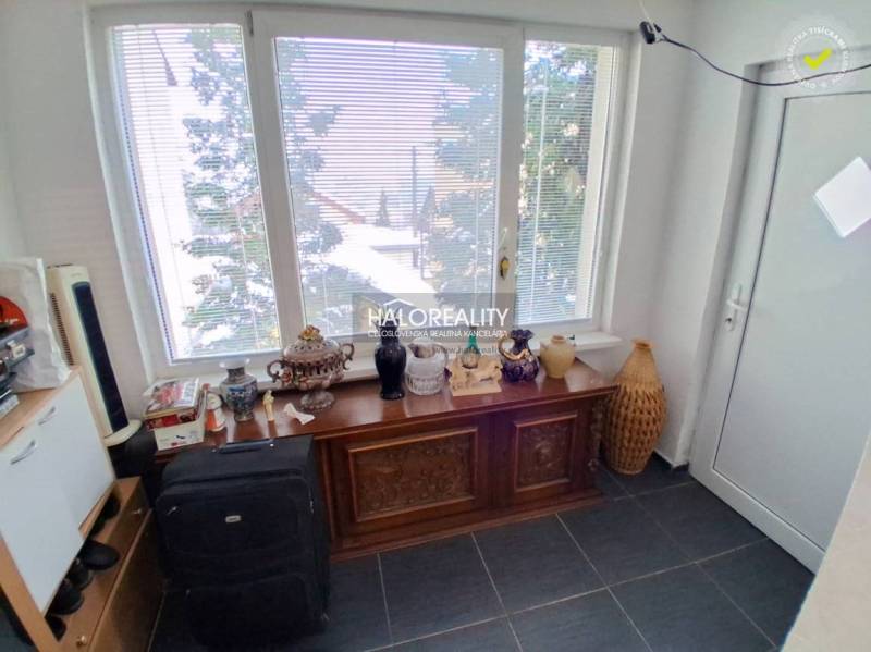 A room with a large window, a decorative dresser, and various items in a family house.